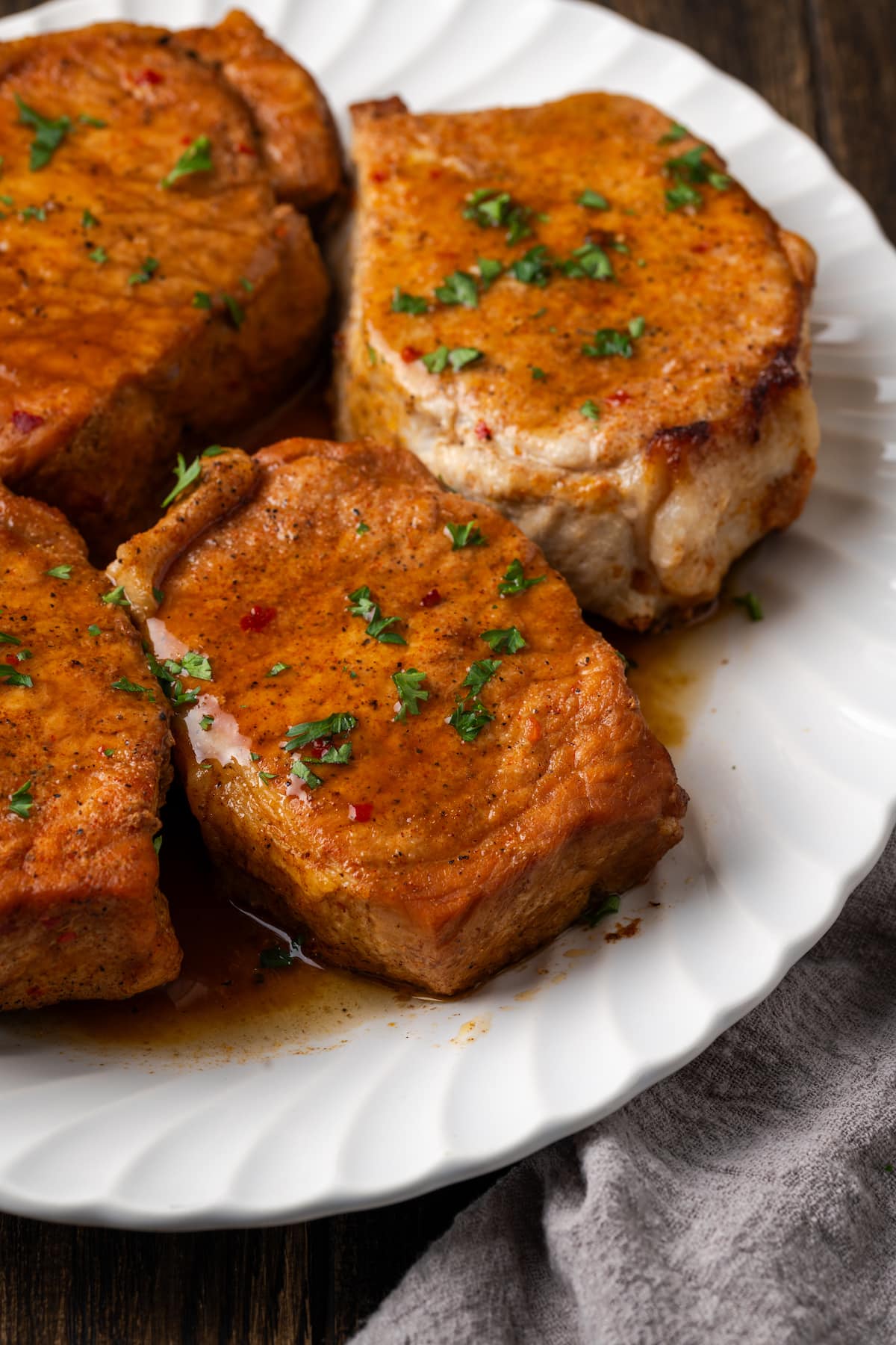 Instant pot pork chops on a white platter garnished with fresh parsley.