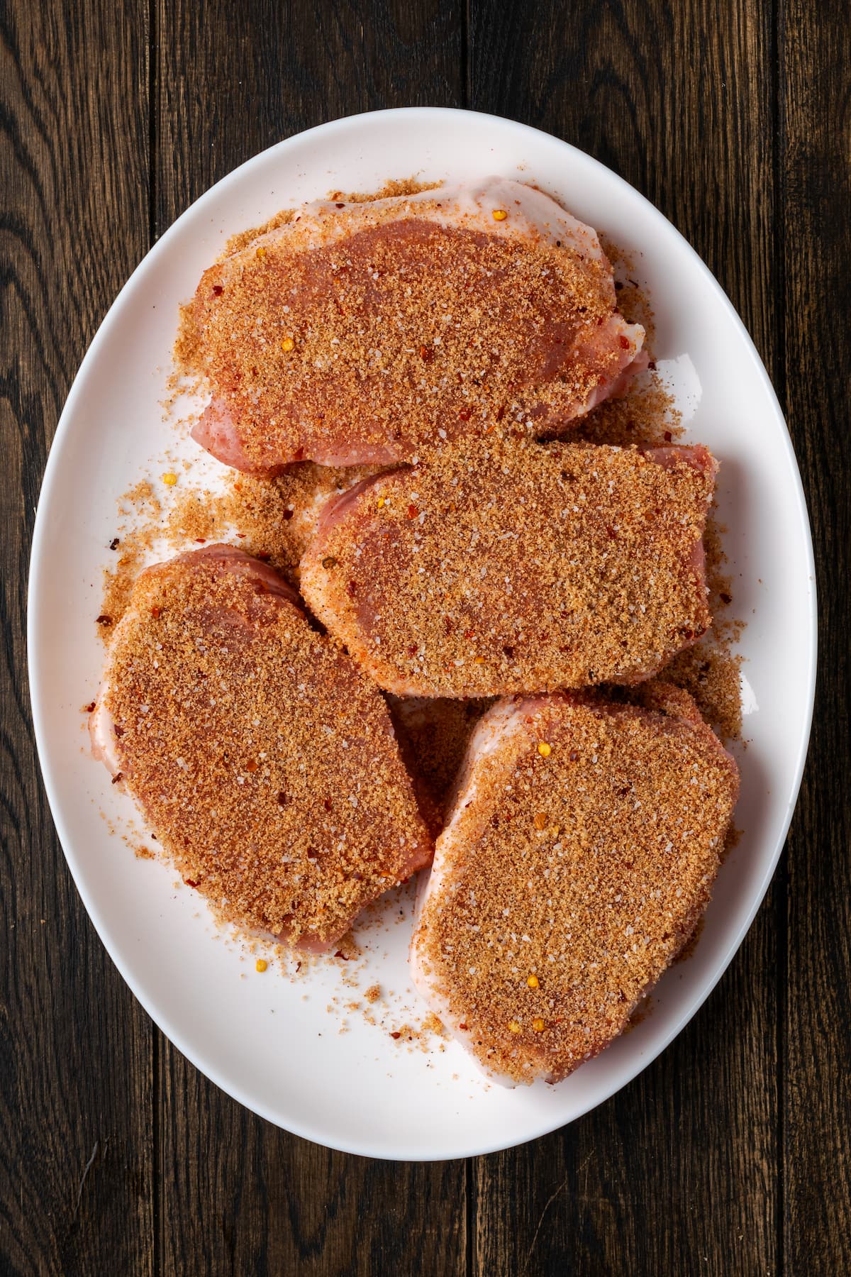 Seasoned pork chops on a white plate.