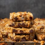 Side view of a stack of magic bars on a wooden countertop, with more bars in the background.