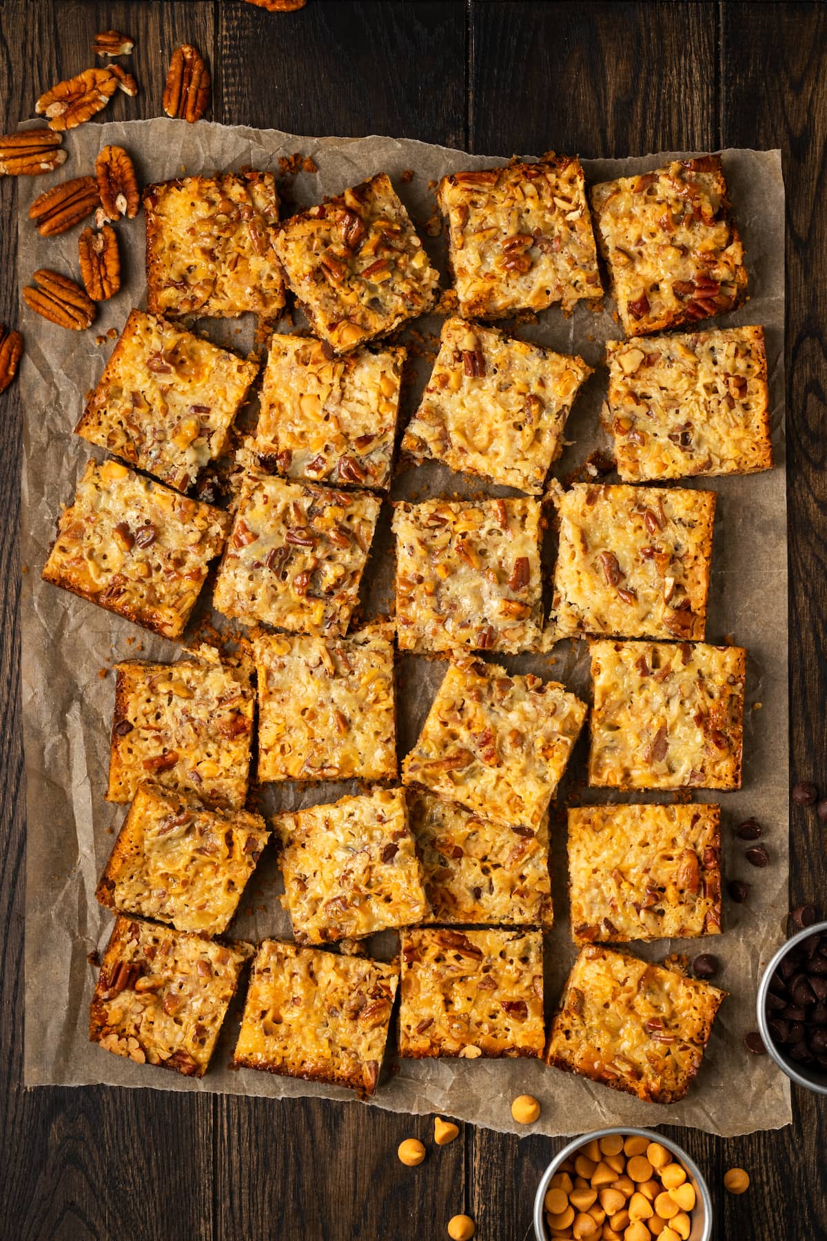 Overhead view of magic bars cut into squares on a sheet of parchment paper.