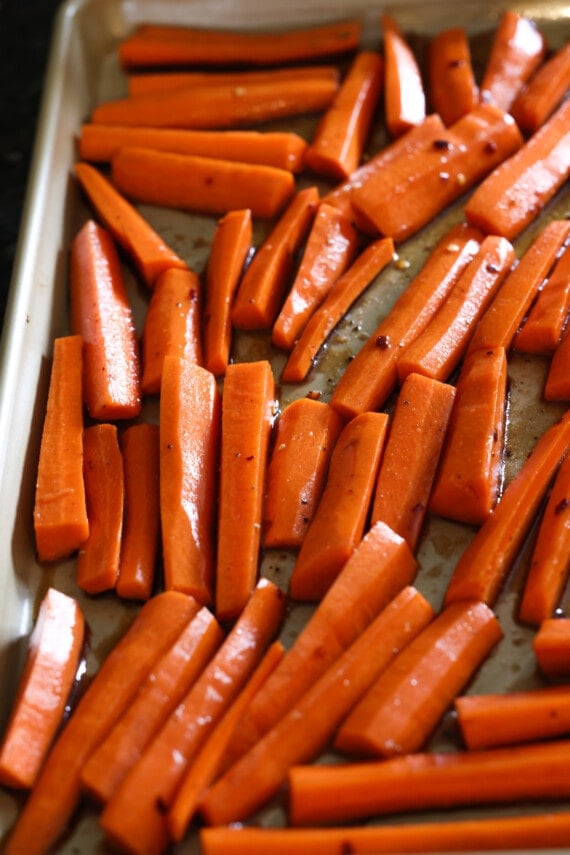 Matchstick cut carrots coated in seasoning and a balsamic vinegar glaze on a baking sheet