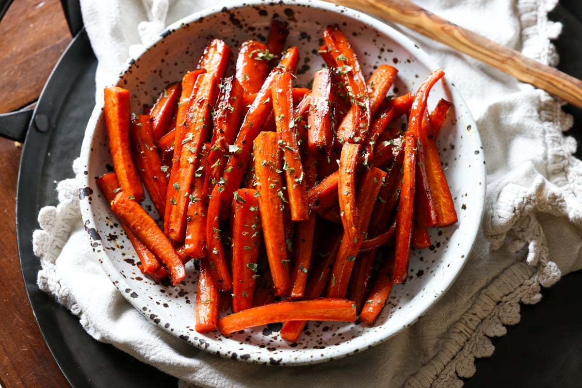 Sliced roasted carrots in a ceramic bowl from above garnished with parsley