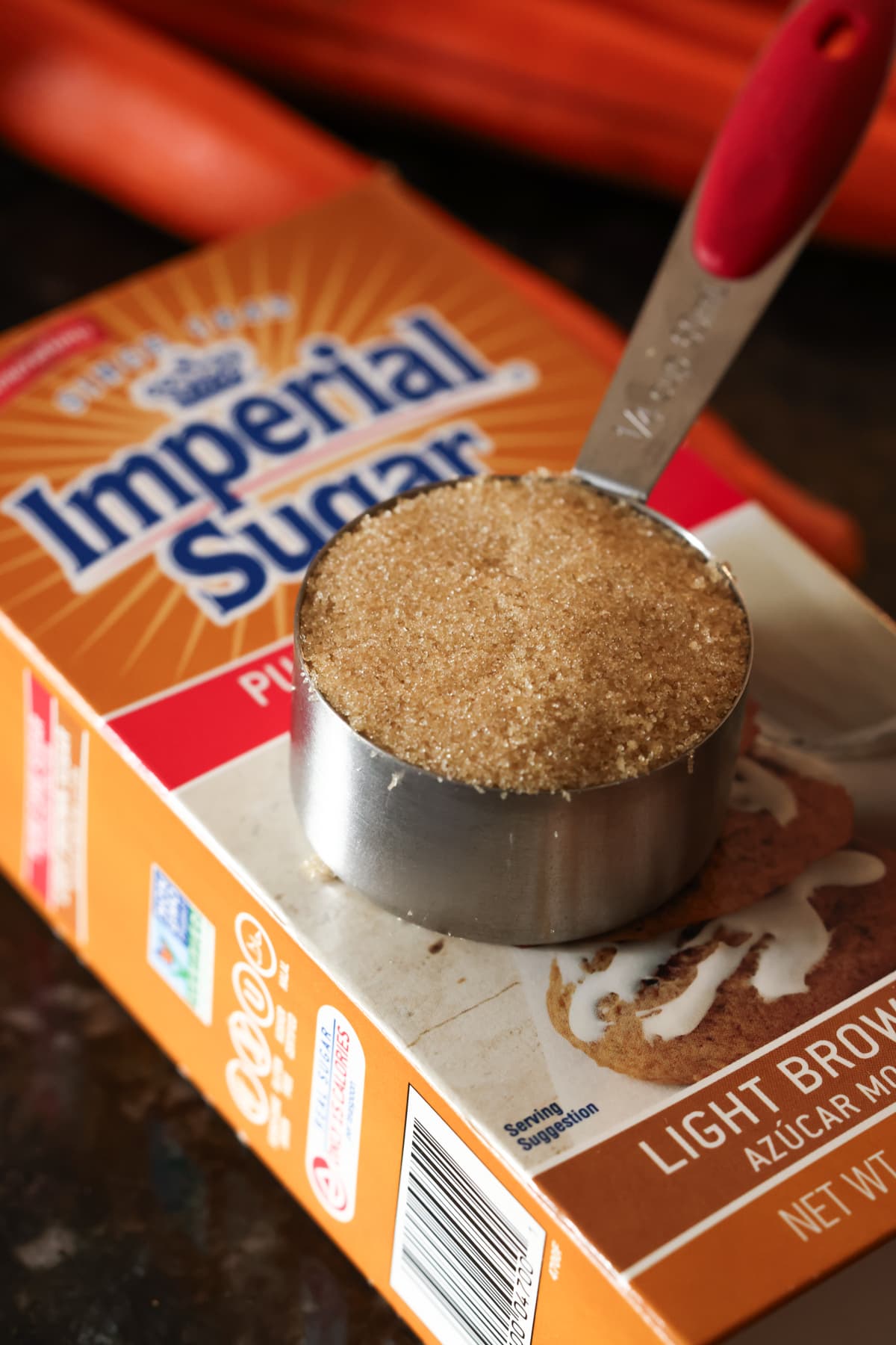 1/4 cup of brown sugar in a measuring cup on top of a box of Imperial Sugar
