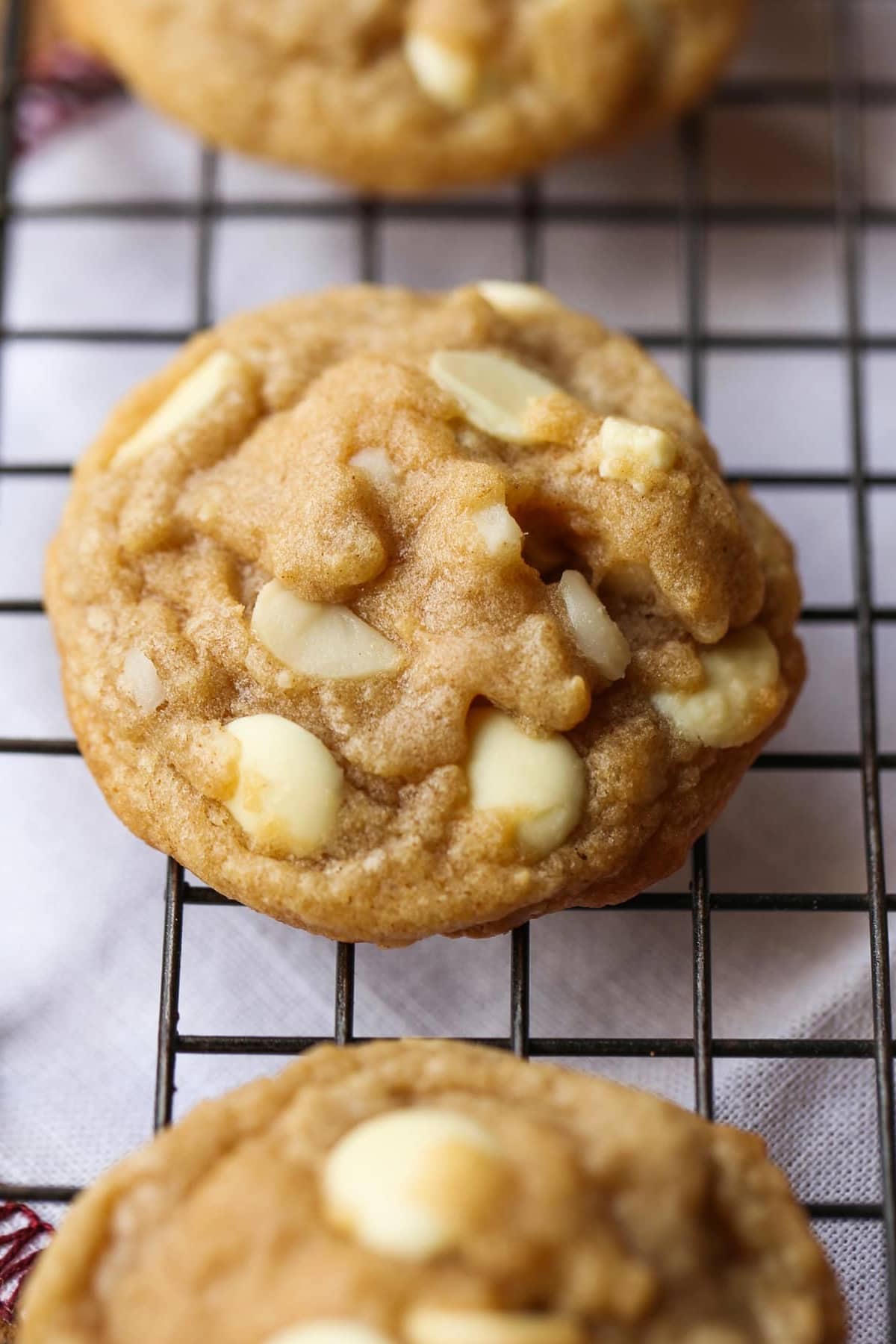 A baked white chocolate macadamia nut cookie on a wire cooling rack
