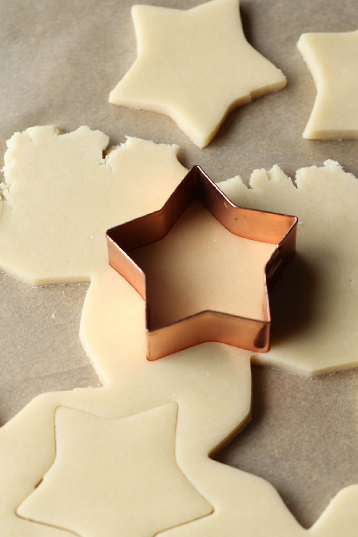 cutting out sugar cookie dough with a star shaped cookie cutter
