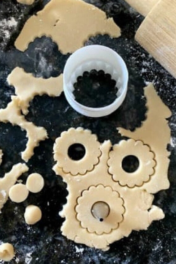 Cutting out the cookie dough for Linzer cookies on a floured surface.