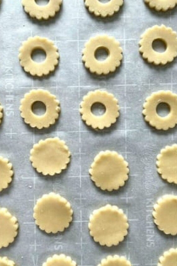 Overhead view of shortbread cookie dough cut-out into rounds, some with a small hole cut in the center.