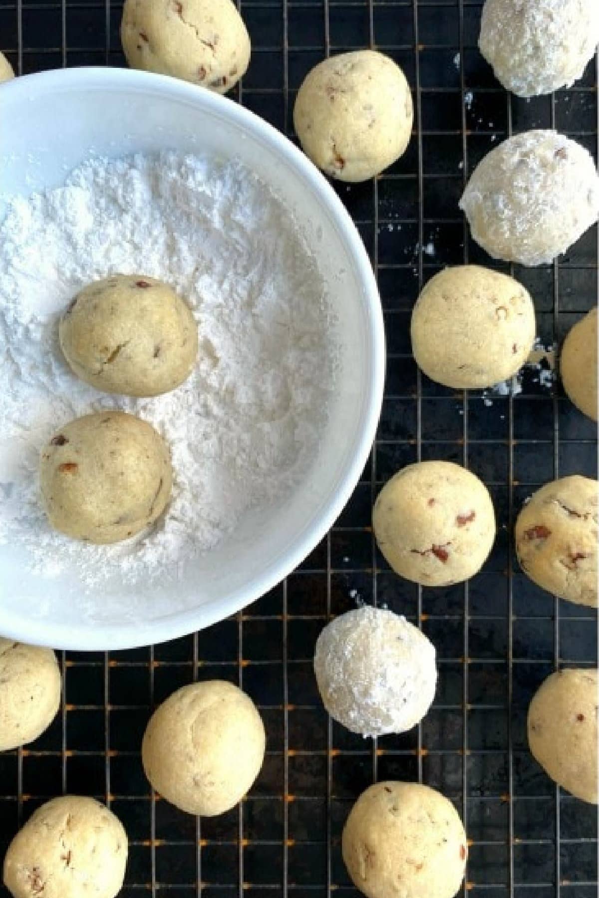 Rolling baked Russian Tea Cakes in Powdered Sugar