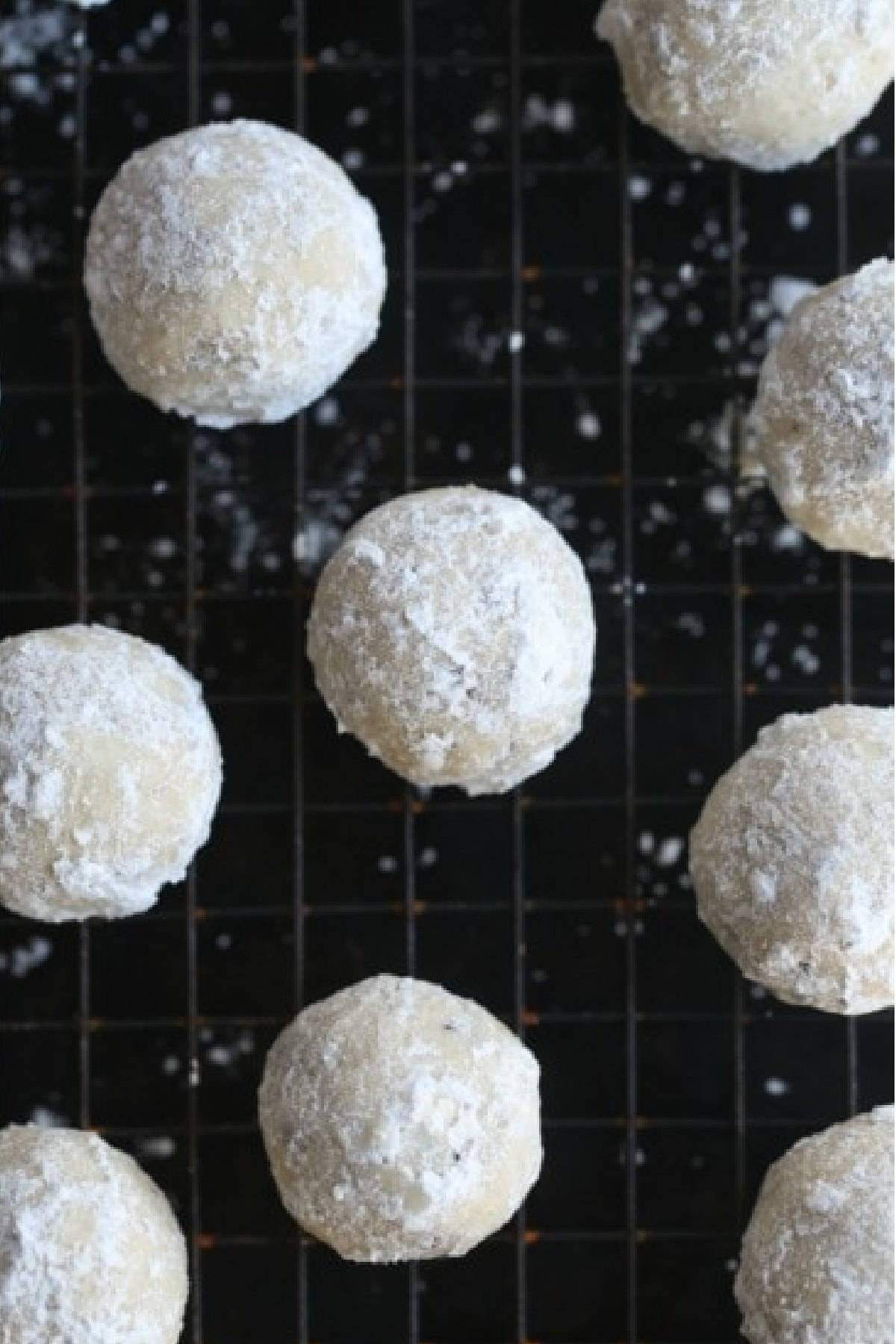 Powdered Sugar Coated Snowball Cookies on a wire cooling rack