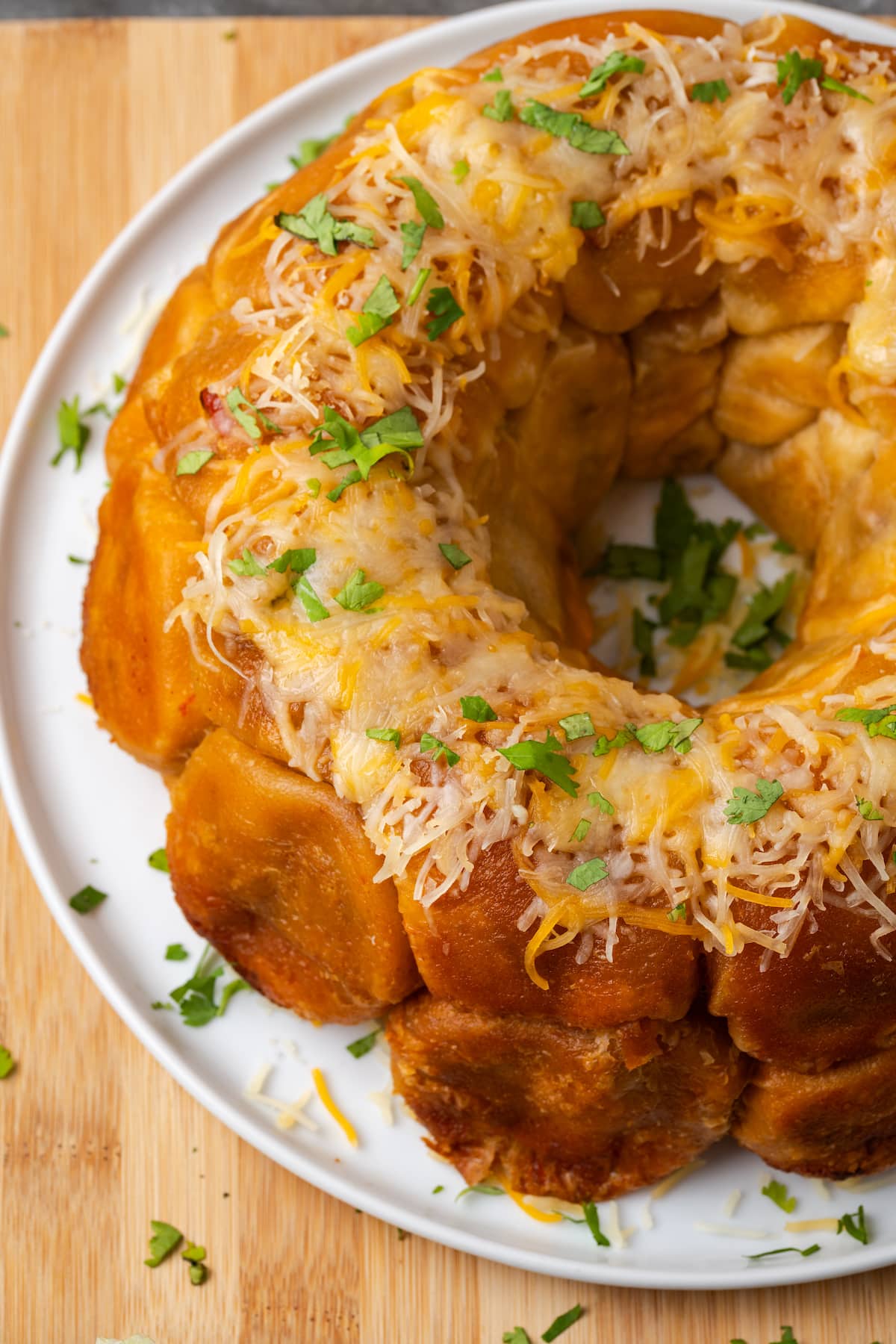 Taco monkey bread topped with melted cheese on a white plate.