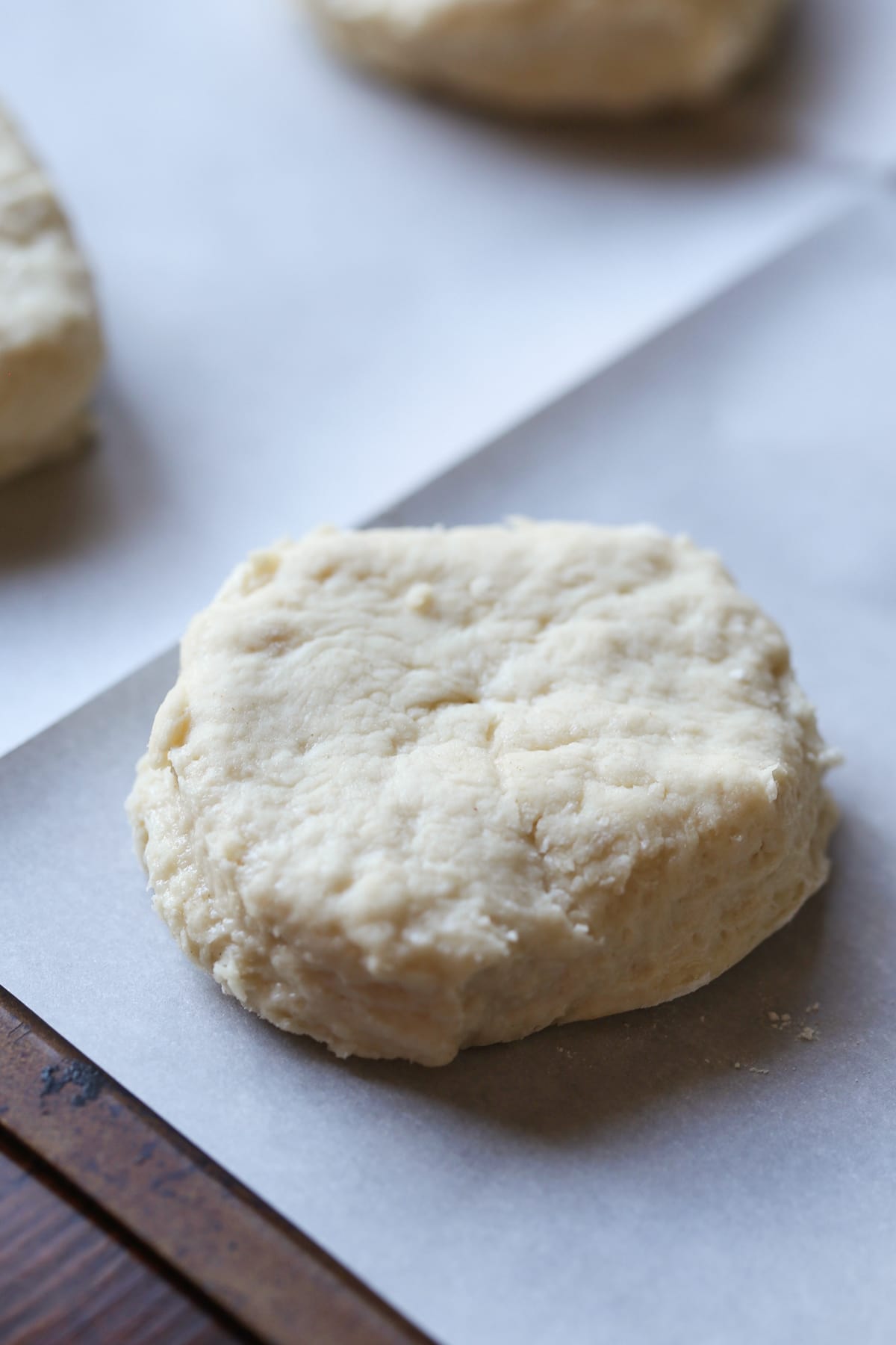 Biscuit dough cut into rounds on a parchment lined baking sheet.
