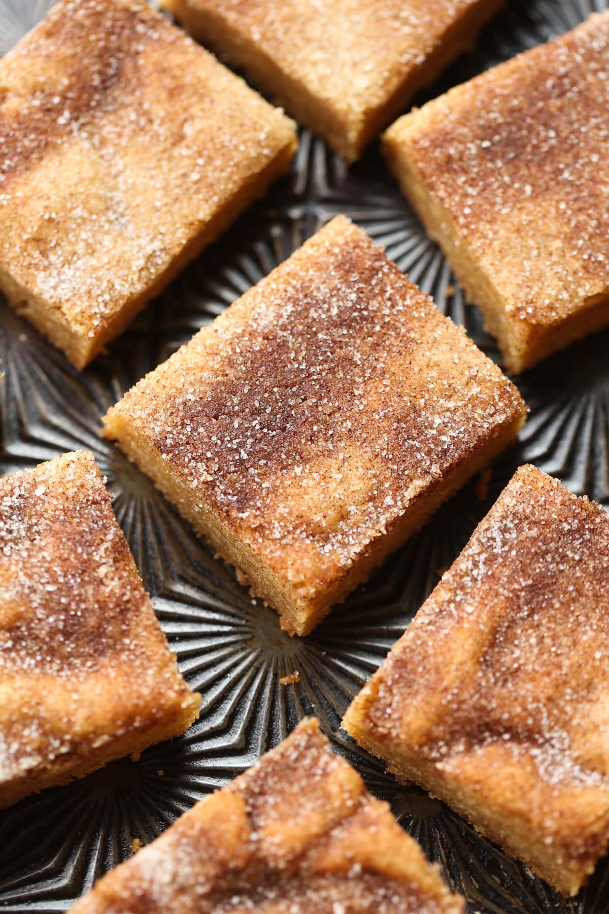 Cookie bars made with browned butter and topped with cinnamon sugar cut into squares on a baking sheet