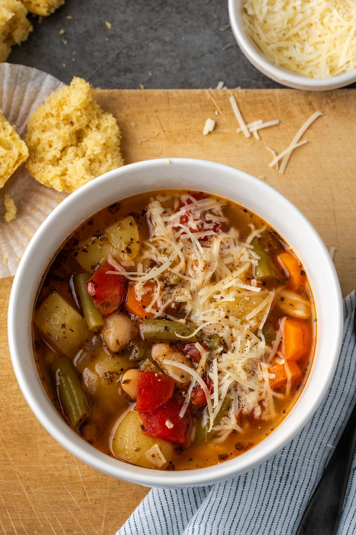 Overhead view of a bowl of instant pot vegetable soup next to a cornbread muffin.