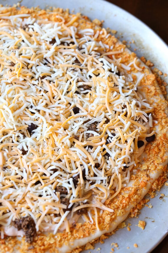 Pizza crust topped with taco meat and shredded cheese.