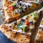 Close up of a taco pizza cut into slices on a pizza pan.
