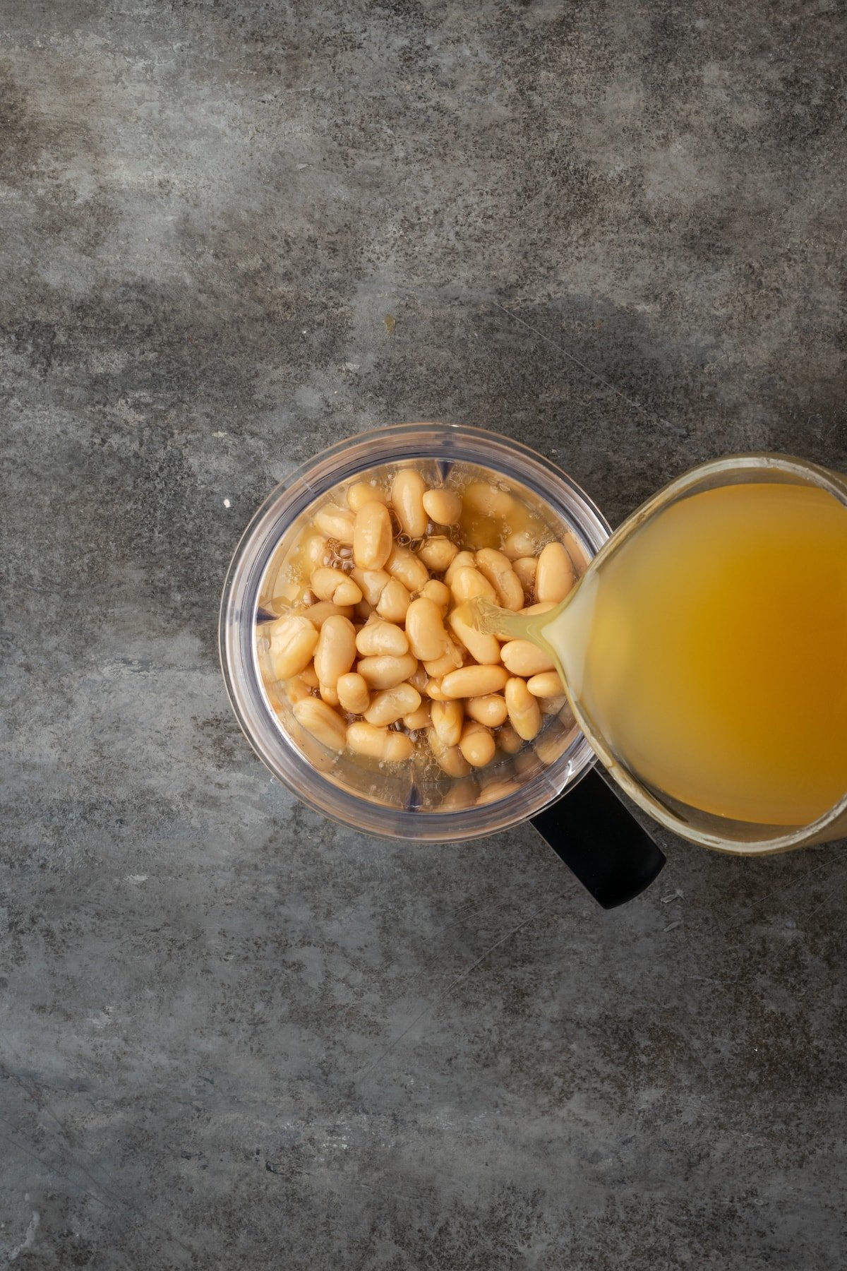 Broth added to white beans in a blender.