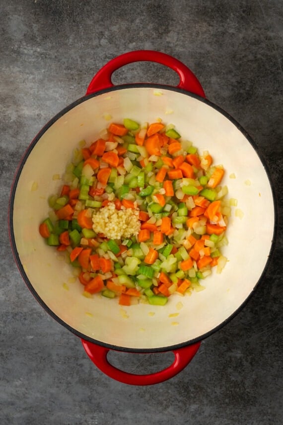 Diced carrots, onion, and celery sauteeing in a large pot.
