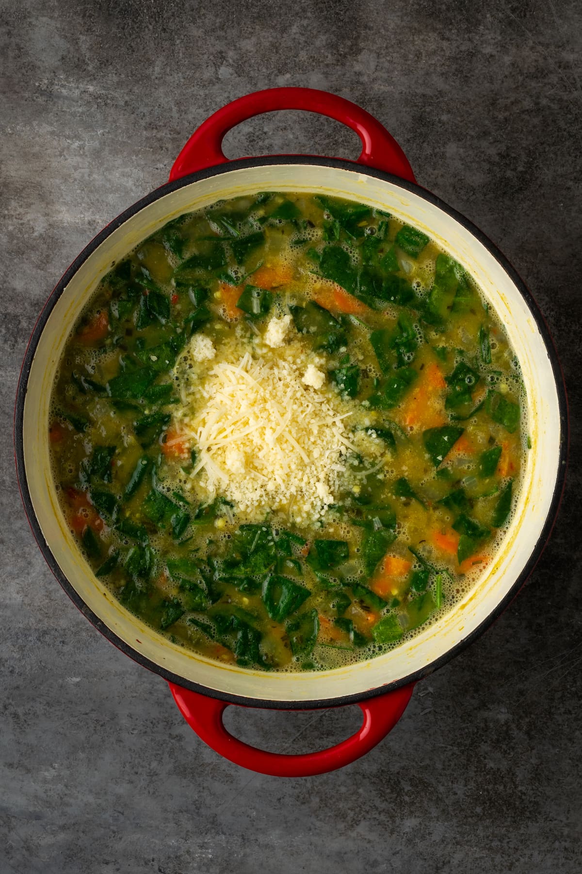 Parmesan cheese added to a pot of white bean soup.