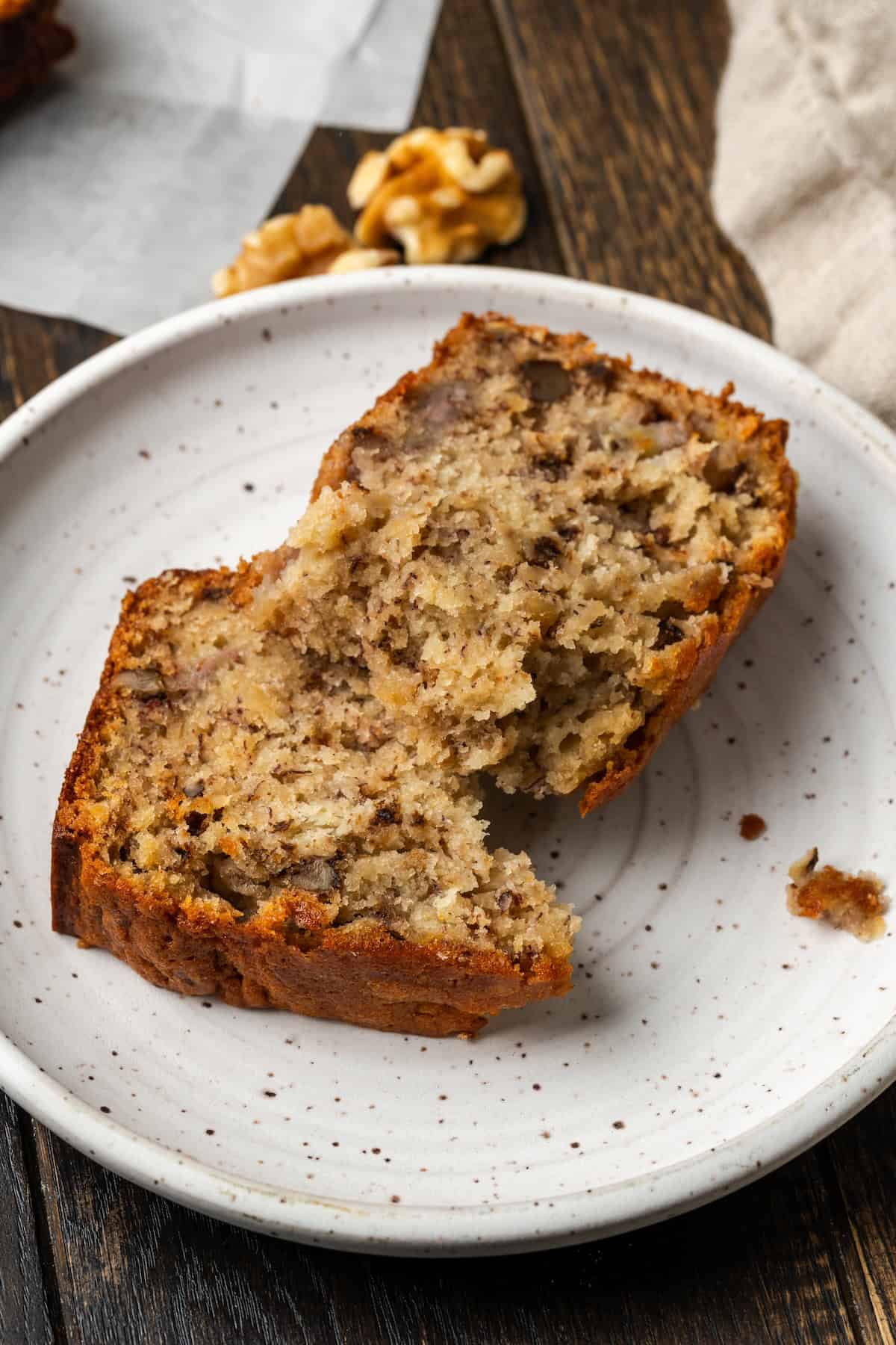 A slice of banana bread broken in half on a plate.