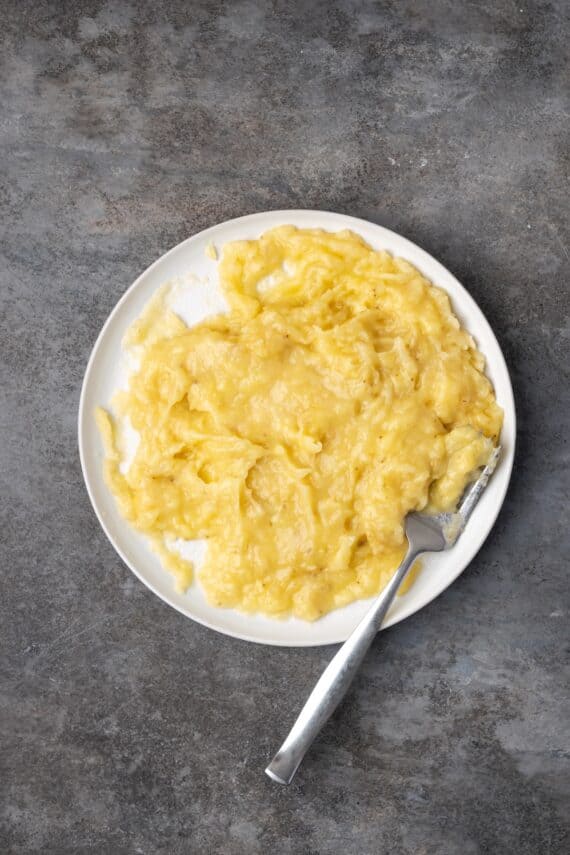 Mashed bananas on a plate with a fork.
