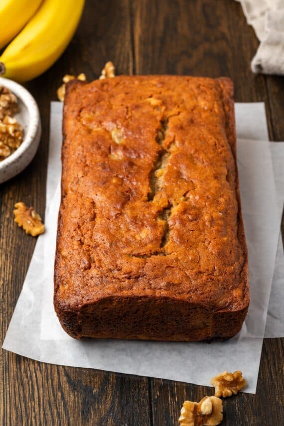 A baked banana bread loaf on sheets of parchment paper.
