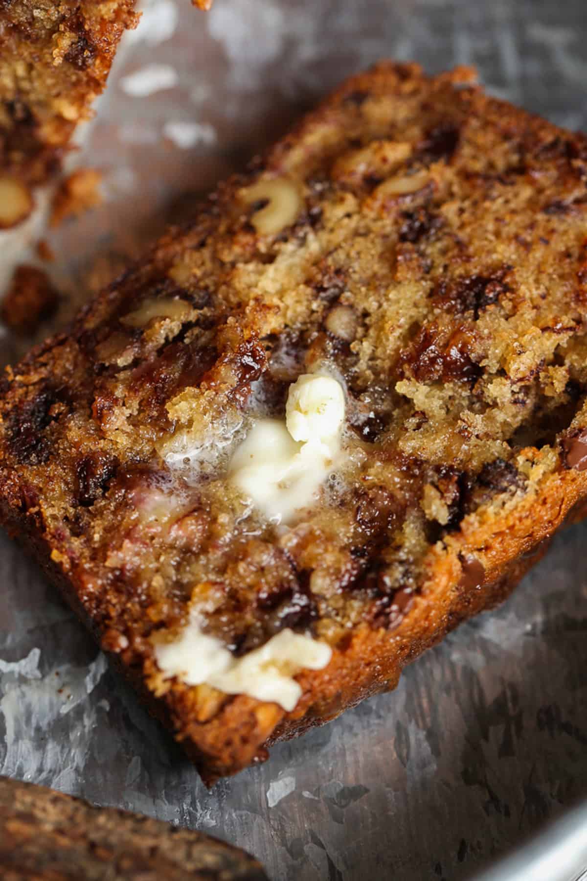 A slice of chocolate chip banana bread topped with melted butter.