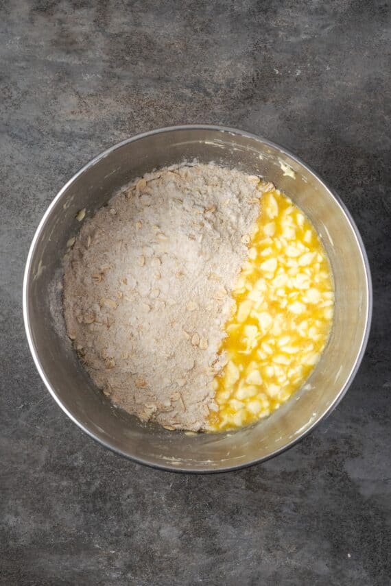 This easy cornflake cookies recipe makes chewy, buttery cookies packed with gooey chocolate chips and nostalgic cornflake cereal crunch! Dry ingredients added to wet ingredients in a bowl.