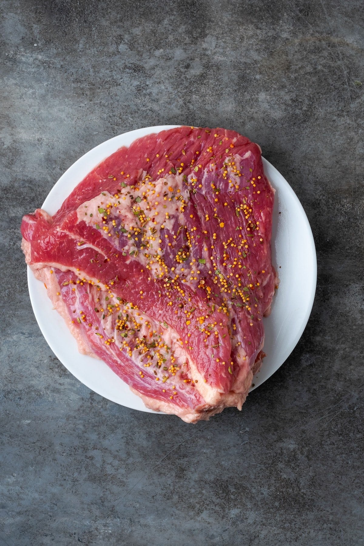 Uncooked corned beef brisket on a plate.