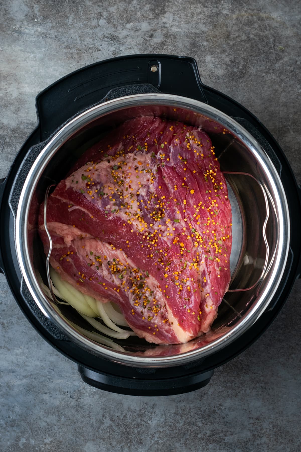 Corned beef placed over top of chopped onions in the instant pot.