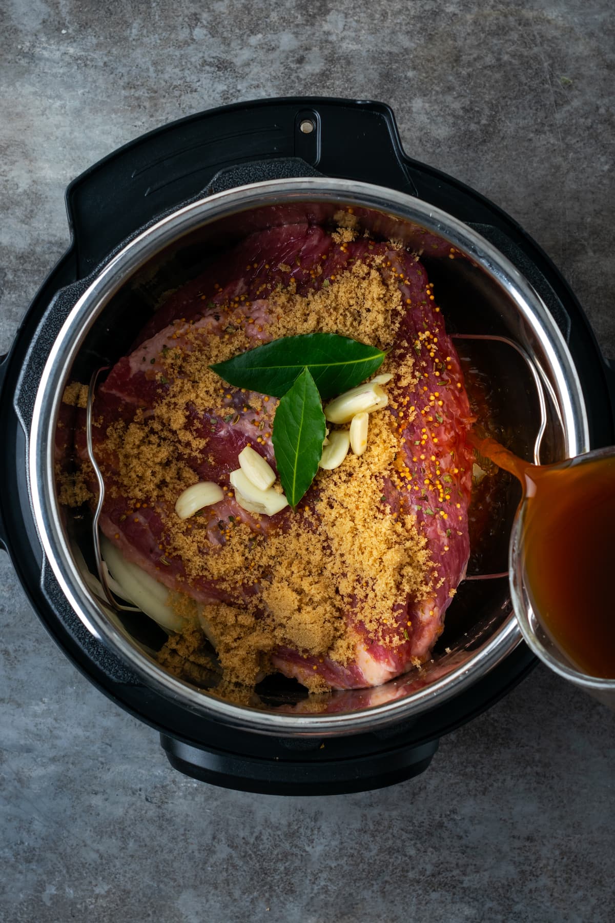 Seasonings and broth being added to corned beef inside the instant pot.