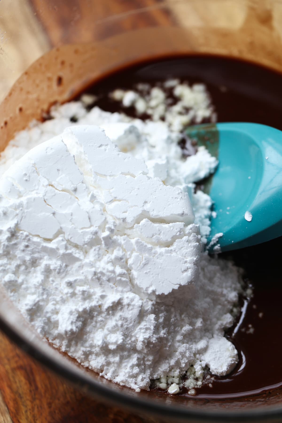 Adding powdered sugar to chocolate cake batter in a mixing bowl