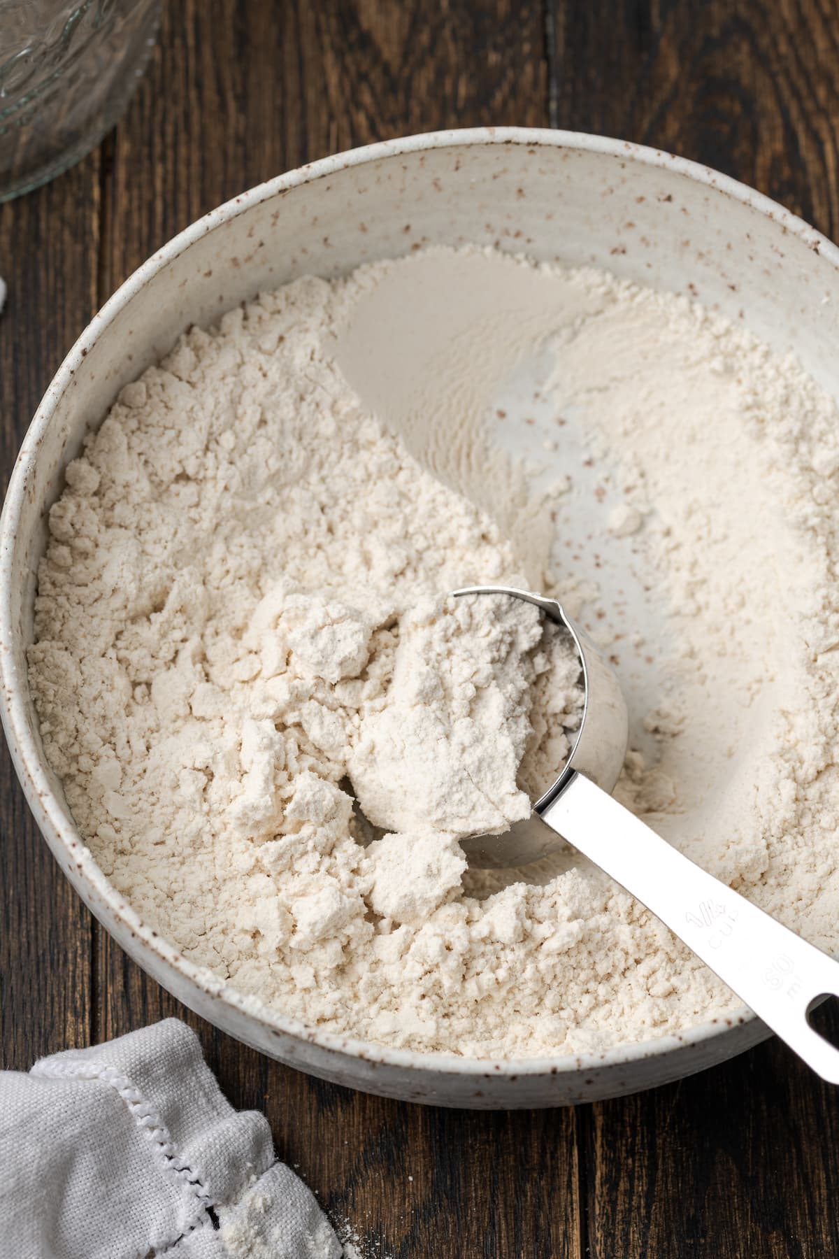 A bowl of self rising flour with a measuring spoon.