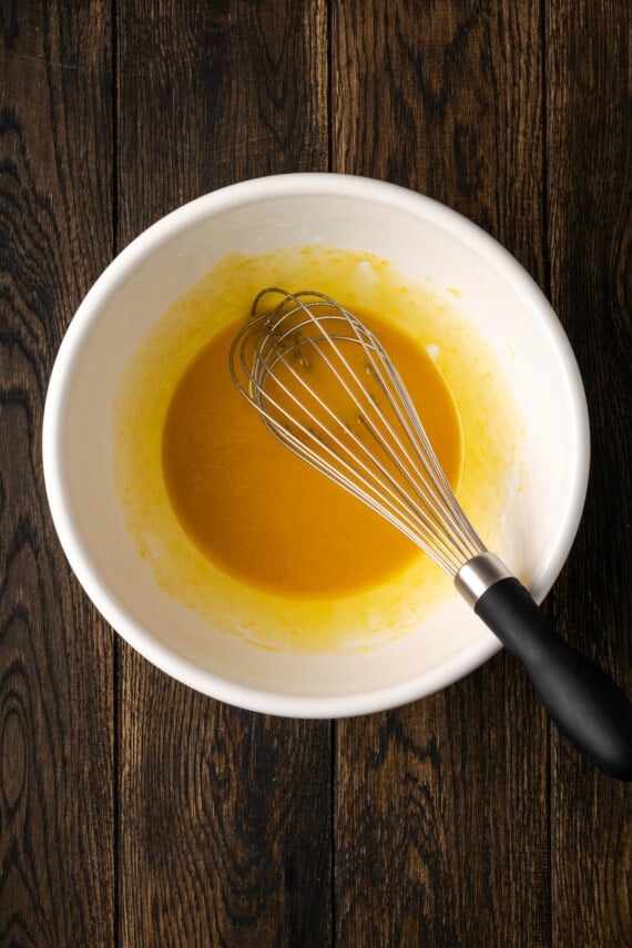 Wet waffle batter ingredients whisked together in a bowl.