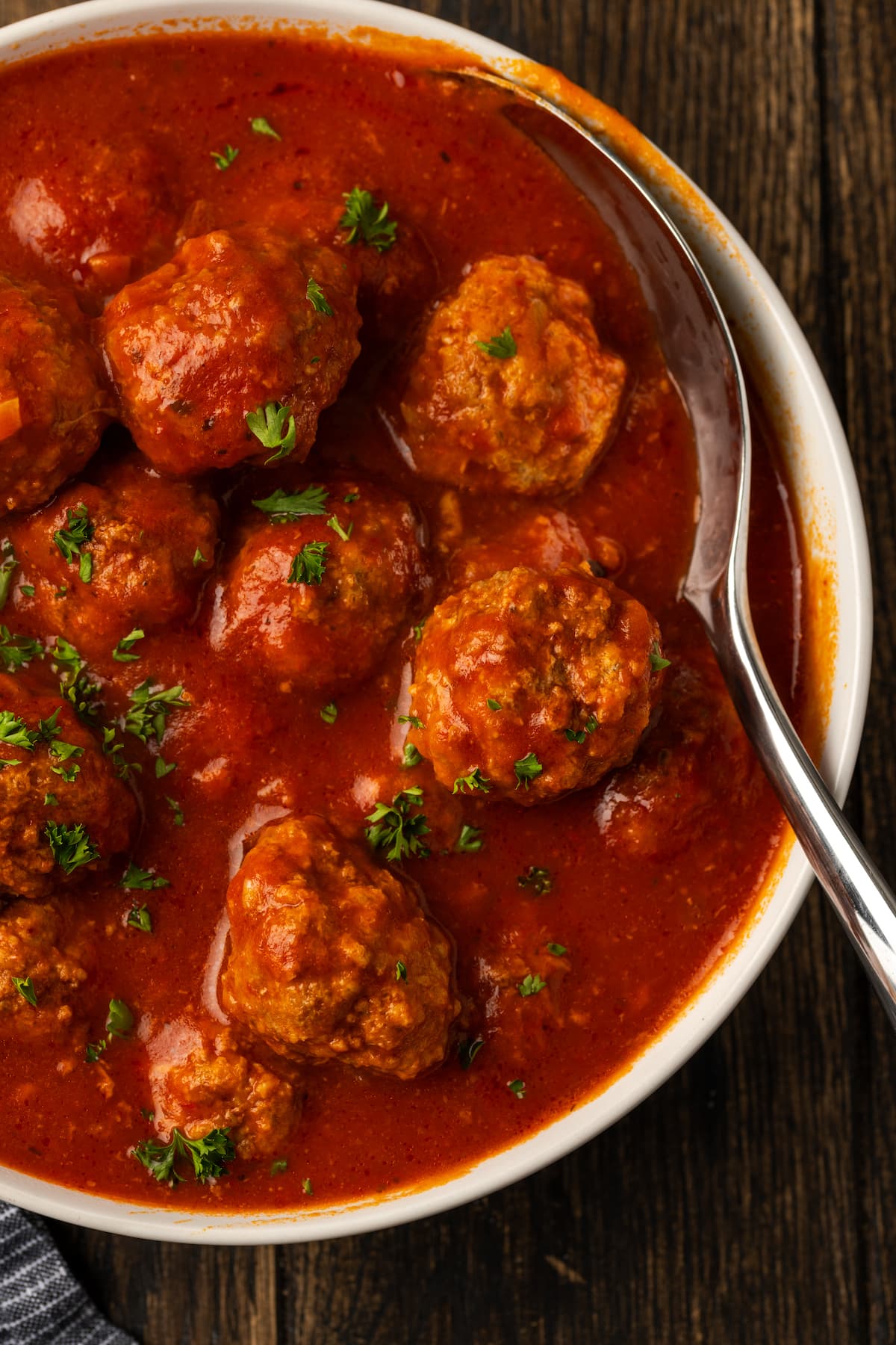 Overhead view of instant pot meatballs served in a bowl with pasta sauce, with a spoon for serving.