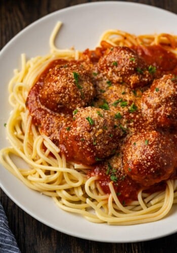 Instant pot meatballs and sauce served over a bed of spaghetti on a white plate.