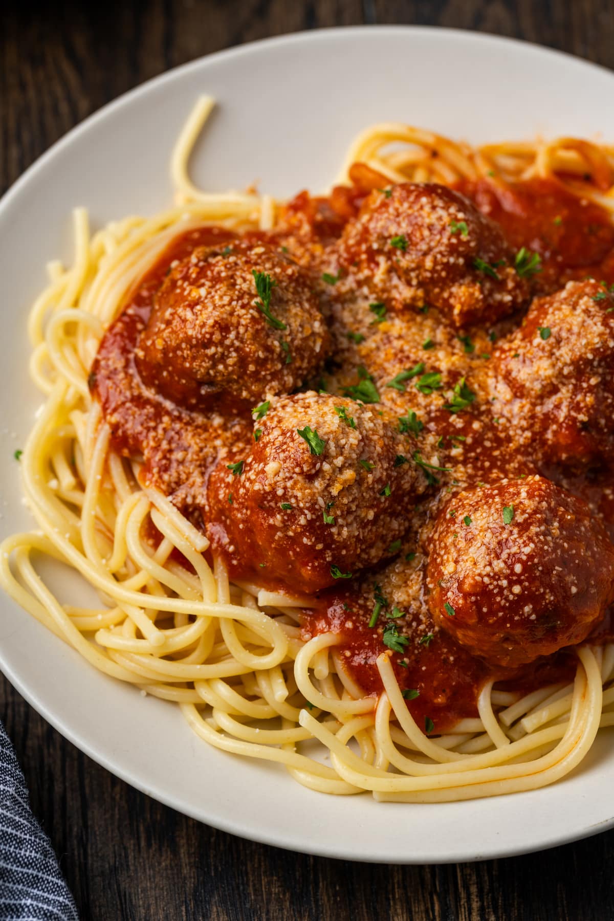 Instant pot meatballs and sauce served over a bed of spaghetti on a white plate.
