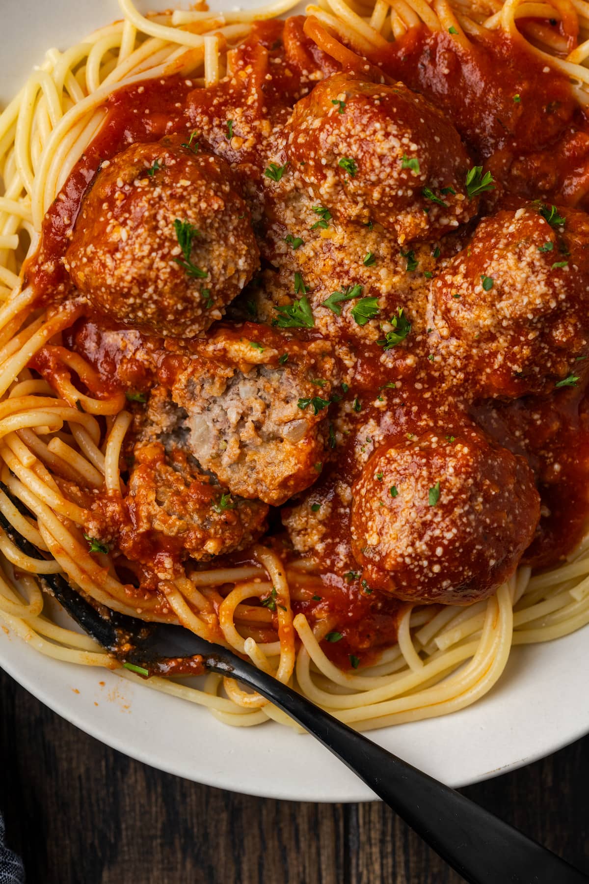 Overhead view of instant pot meatballs and sauce served over a bed of spaghetti on a white plate with a fork.