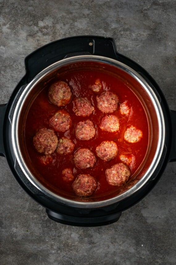 Meatballs nestled into pasta sauce inside the instant pot.