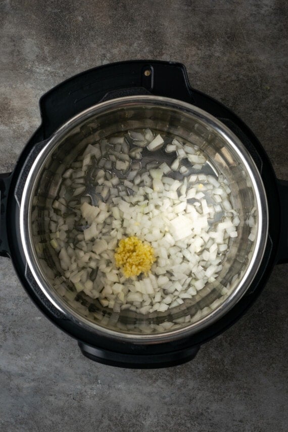 Diced onions and garlic inside the instant pot.