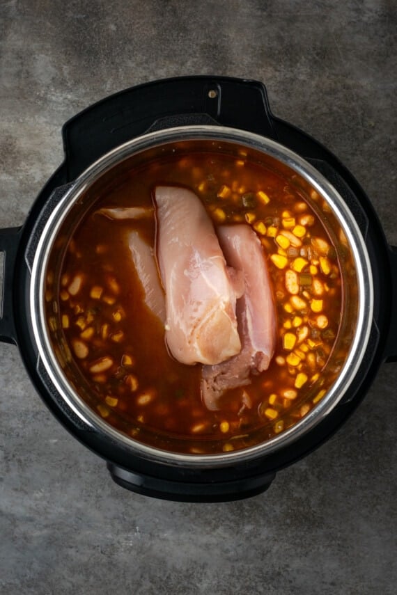 Chicken breast and chili ingredients combined inside the instant pot.