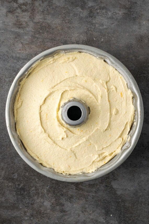 Meyer lemon cake batter spread into a bundt pan.