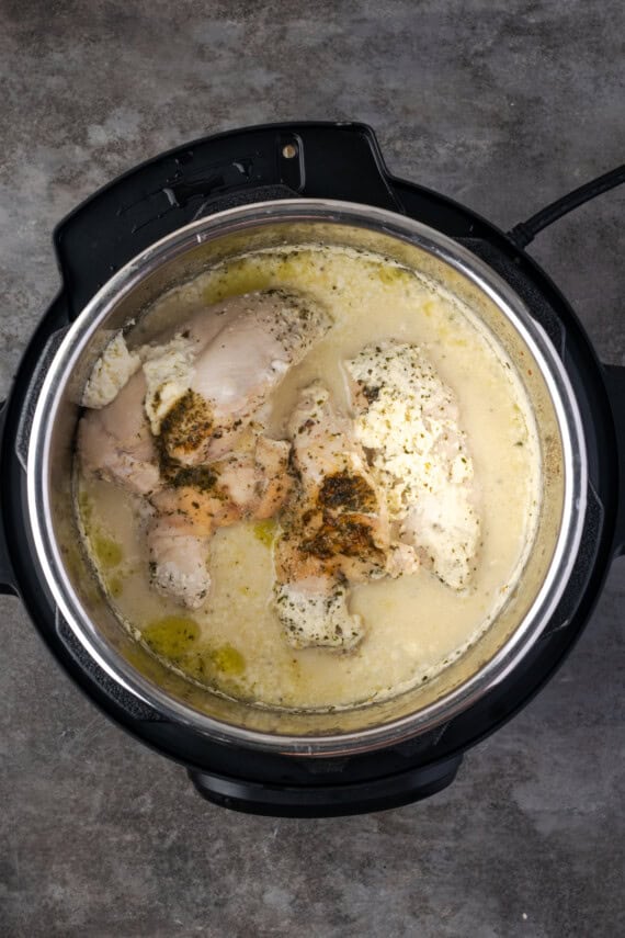 Cooked chicken in a creamy broth inside the instant pot.