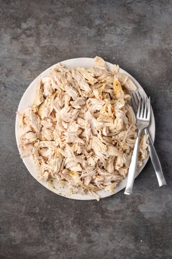 Shredded chicken on a plate next to two forks.