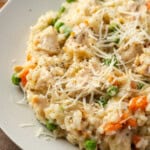 Close up of chicken and rice garnished with grated parmesan in a white bowl.