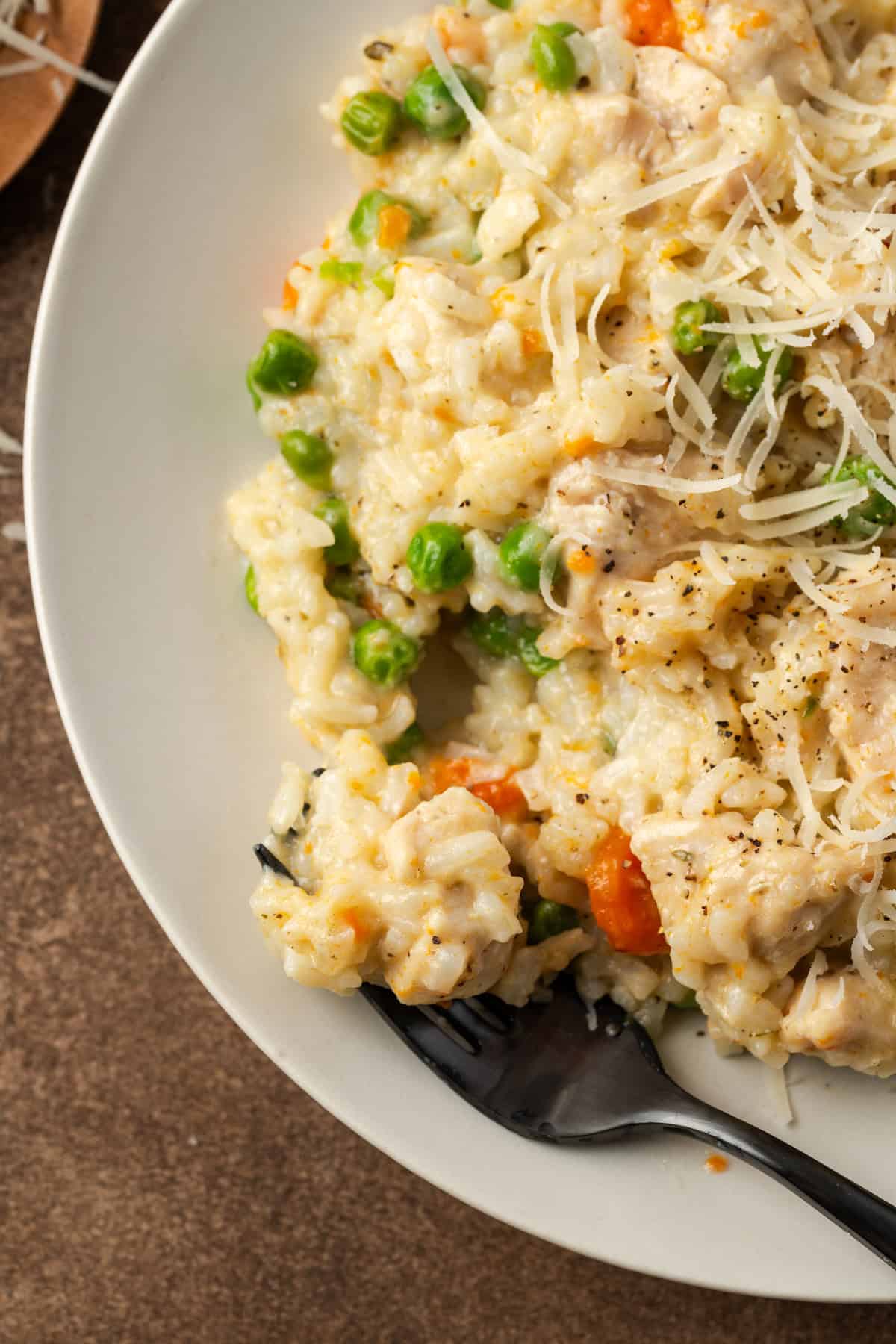 Close up of a forkful resting in a bowl of chicken and rice garnished with grated parmesan.