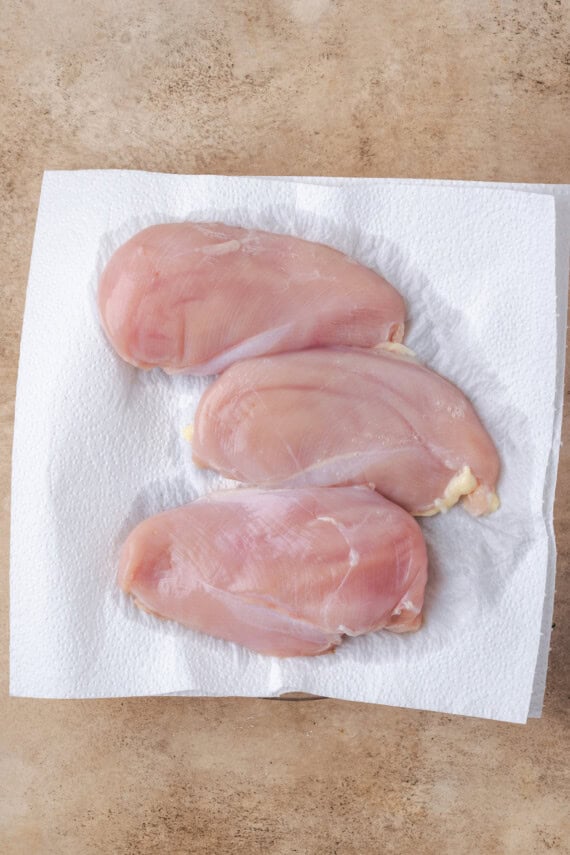Three brined chicken breasts on a paper towel-lined plate.