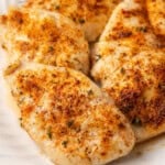 Baked chicken breasts on a large white platter.