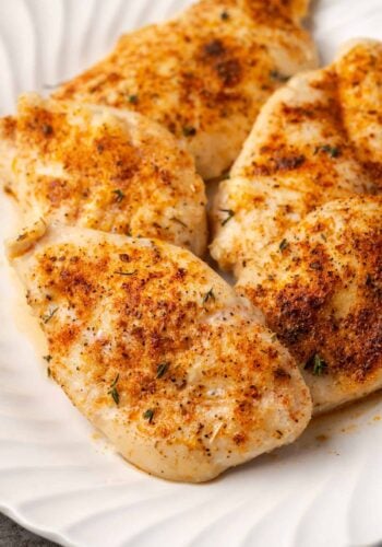 Baked chicken breasts on a large white platter.