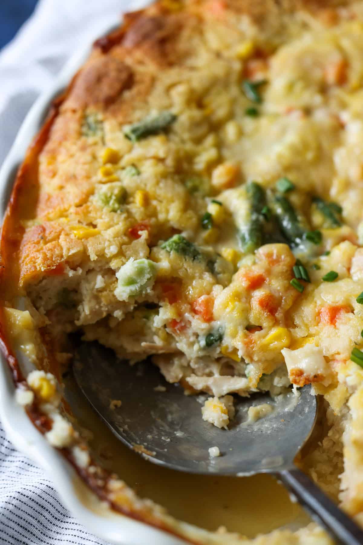 Scooping out a serving of chicken cobbler with a serving spoon