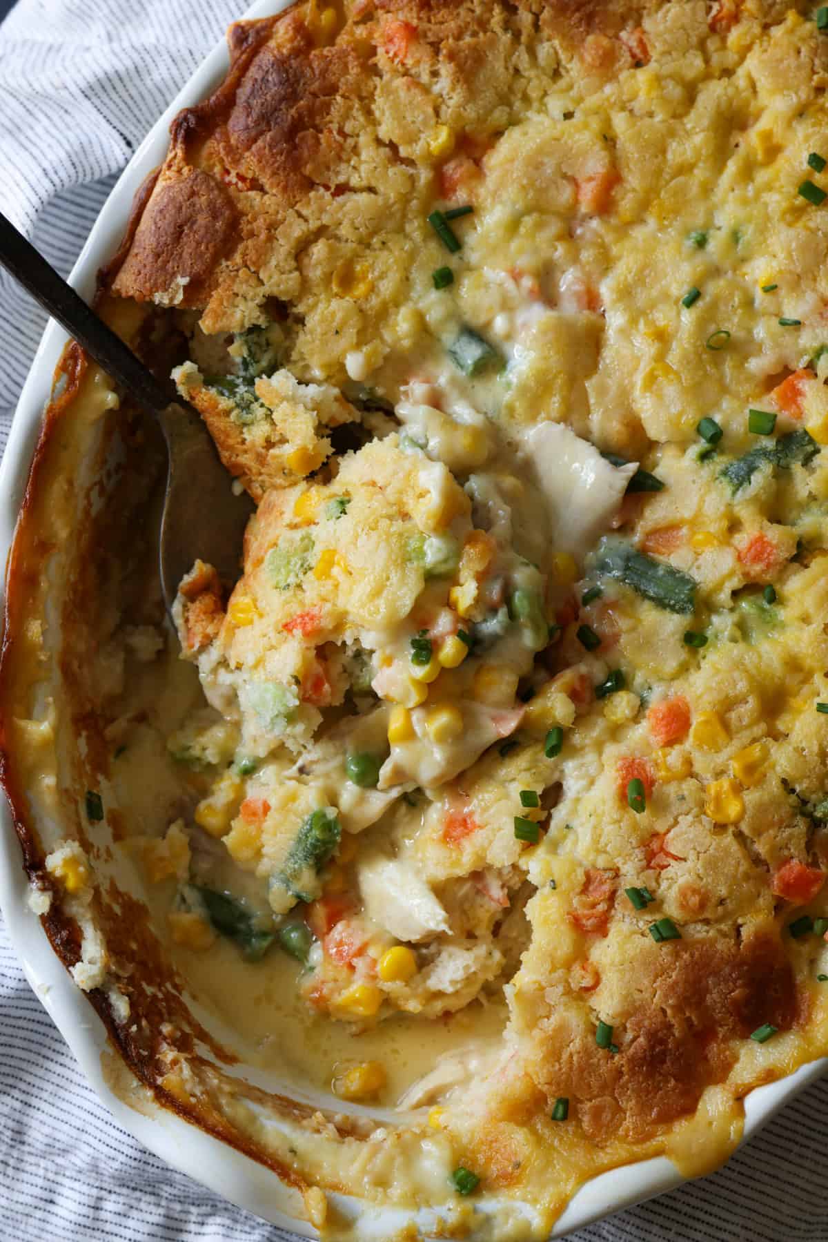 TikTok Chicken Cobbler casserole baked in a round dish with a spoon scooping out a portion